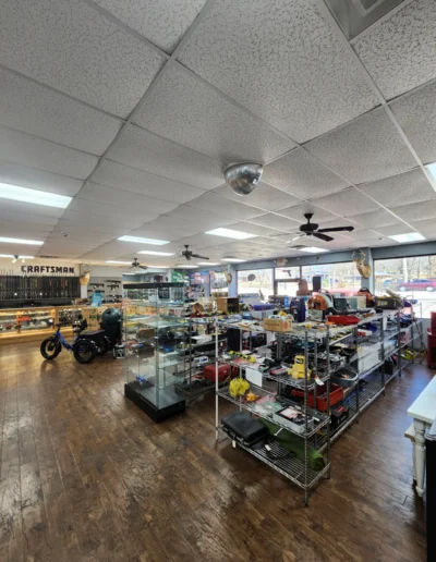 Wide view of a retail floor featuring metal shelving units stocked with tools and outdoor equipment.