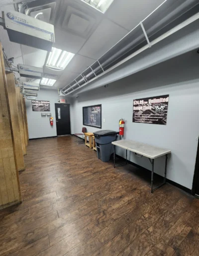 The staging area of an indoor shooting range featuring wooden partitions, target retrieval controls, and safety equipment.