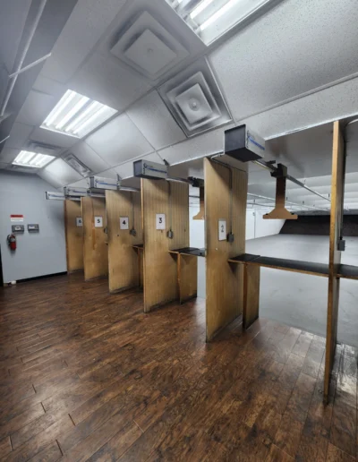 A row of numbered wooden shooting stalls at an indoor range equipped with Action Target retrieval systems.